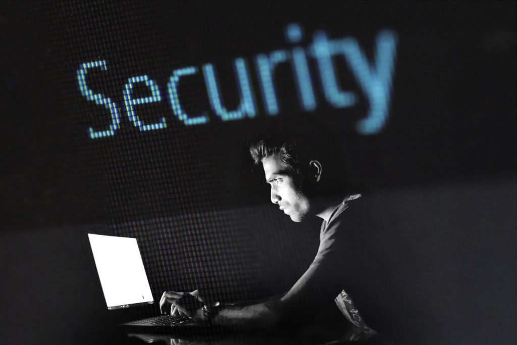 Image of a person on a laptop in a dark room with the word security above them