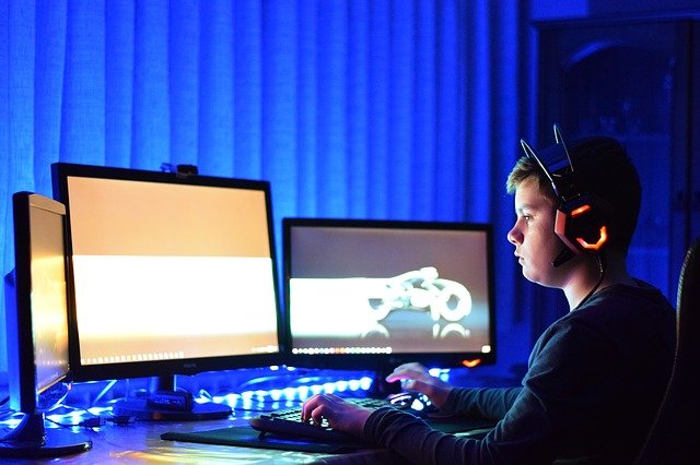 gamer with headset and three monitors