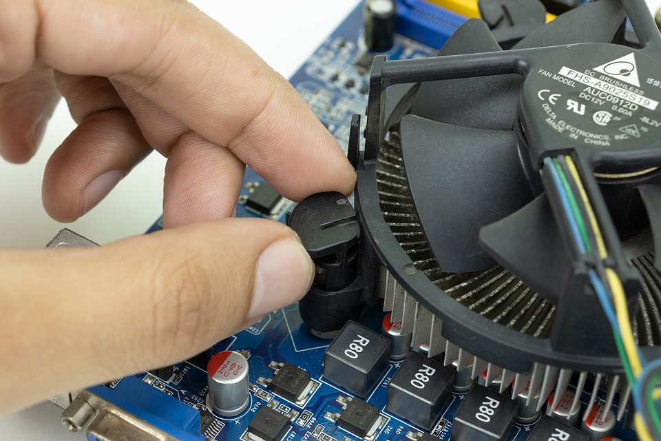 Image of fingers touching the mounting clamp on an Intel stock CPU cooler